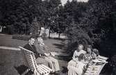 Kvinnor och män fotograferade sittandes i trädgården, Stretered i Kållered. Ivar Andersson sitter till vänster. 