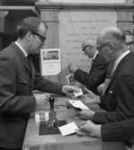 Museets vaktmästare Nils Svensson säljer och stämplar dagens
musei-brevkort till besökarna.