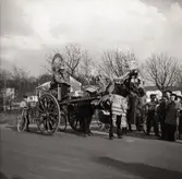 Motiv från Solängen. Häst med vagn och kusk bär dekorationer. Möjligtvis reklam av något slag? Skylt med texten 