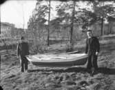 Hopfällbar båt med två åror buren av två män