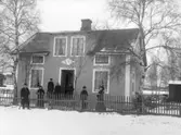 Familj (?) utanför hus. Enligt notering Sebergs gård.