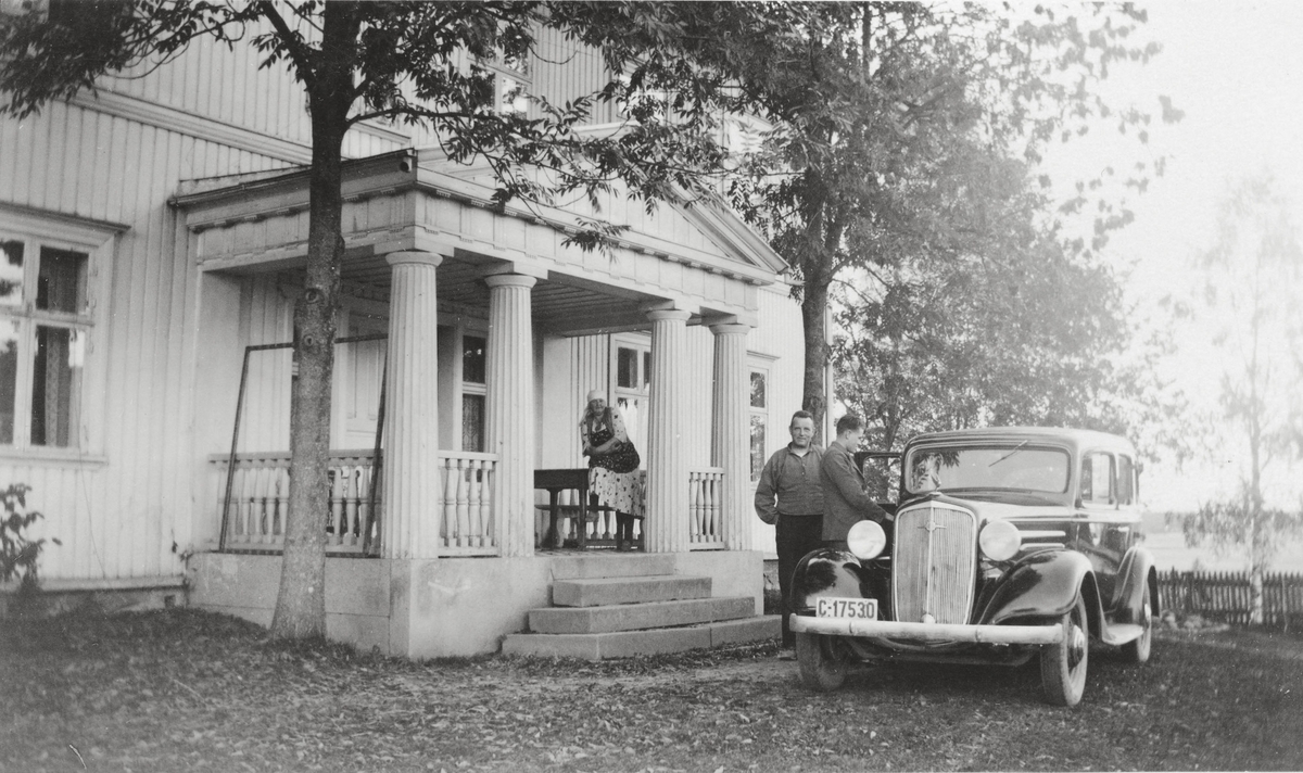 Forsiden av den tidligere hovedbygningen på Frogner gård i Ullensaker.
En dame på trappen og to menn ved bil.