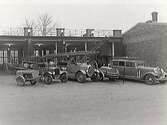 Brandkårens vagnhall på Engelbrektsgatan 5. Inne i vagnhallen till vänster syns en ångspruta. Ute på planen från vänster står en skumspruta, en brandbil T-Ford från 1918-1919, en brandbil Tidaholm från omkring 1928, en motorspruta, en personbil Lincoln utrustad som en utryckningsbil.