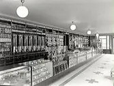 Interiör från Helge Nilssons speceributik 1936. Affären låg på hörnet Borgmästaregatan-Östra Långgatan, Kv Färgaren. Varorna ligger på hyllor bakom en lång disk. Det ligger varor även i glasmontrar under disken.