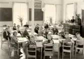 Eleverna i sina skolbänkar i Alltorps skola vänder sig mot kameran, 1940-tal