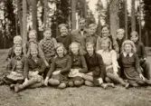 Skolklass sitter på gräsmattan vid Alltorps skola, 1940-tal