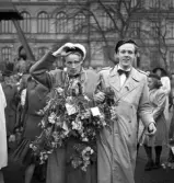 Andra dagens studenter, 1944.
En student med massor av blommor om halsen, eskorteras av en god vän i skolmössa.