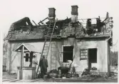 Broakullamordet 1952. Poliskonstapel Bengt Skoog längst till höger undersöker aska från det utbrända huset.