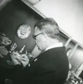 Kungabesök av kung Gustav VI Adolf på Gävle Museum där han står och studerar ingående porslinet, 1946.