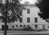 Bil parkerad under tak framför Adolfsbergsskolans entré, 1948