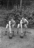 En yngre och en äldre man (från vänster) med kopplingar till atletklubben Heros poserar med kulhantlar utomhus tidigt 1900-tal.