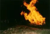 Firande på Störtfjället i Mölndal under valborgsmässoaftonen den 30 april 1998. Människor har samlats vid valborgsmässoelden.