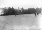 Foto av skolgården vid dåv. Växjö Högre Allmänna Läroverk. 
Det pågår av allt att döma en fotbollsmatch. I bakgrunden skymtar dåv. Växjö lasarett.
