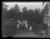 En familj (tre generationer) som samlats utanför staketet till sin sommarvilla, nära en sjö.