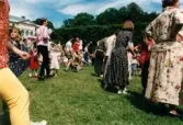 Midsommarfirande vid Gunnebo slott i Mölndal, okänt årtal. Dans kring midsommarstången för små och stora.