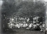 En mängd sommarklädda barn och ungdomar (varav några i Rättviksdräkt) i en park. 
Trol. Varberg.