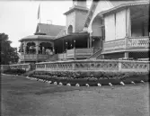 Societetshuset i Varberg, med sina verandor m.m.
I förgrunden en blomrabatt omgärdad av stora snäckor.