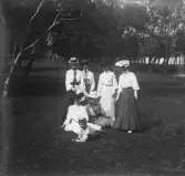 Sex damer i hatt och en pojke, i en park, (trol.) Varberg.