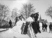 Elever från Årstads skola roar sig i snön på rasten, med Årstads kyrka i bakgrunden.