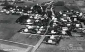 Flygfoto över Vinberg. Stationssamhälle med enfamiljshus och trädgårdar, omgivet av odlingslandskap.