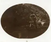 Foto av en pojke sittande på en gunghäst i en trädgård.(enligt text skriven i albumet)