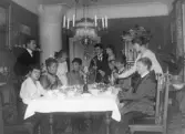 Fotograf Mathilda Ranch har kaffebjudning i sitt hem. Vid bordet sitter Mathilda som nr 2 fr v, systern Nathalia Alling som nr 3 med döttrarna stående, systern Hulda Lind som nr 4 och fru Maria Bäckström med sönerna William och Robert Bäckström stående, samt sonhustrur. Varberg, kv Bagaren, Prästgatan