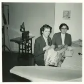 Didners damkonfektion, Växjö.
Två kvinnor är upptagna med ändringsarbete av några kappor.