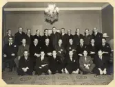 En grupp män i kostym har samlats för gruppfoto, troligtvis i Stockholm. 
Möjligen någon slags fackföreningsmöte (boktryckeri?).