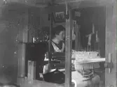 Kvinna som sitter vid en vävstol. Bilden troligen tagen i Gällared eller Okome.