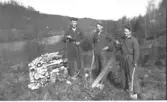 Skogsavverkning för vedeldning? Tornared gård. Tre pojkar i arbetsoveraller med yxa och sågar på en höjd ovanför ett vattendrag. Foto från omkring 1925-1926.