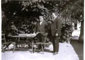 Foto av farbror John och Olle i Vaxholms park och badhotellet (enligt text vid bild i album). Text baksida kort: I Vaxholm 1924.