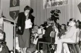 En sammankomst för Unicef i Fässbergsgymnasiets aula i Mölndal, slutet av 1980-talet eller början av 1990-talet. Bland deltagarna ses ordföranden i svenska Unicef-kommittén Lisbeth Palme.