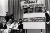 Ordföranden i svenska Unicef-kommittén Lisbeth Palme i talarstolen vid en sammankomst för Unicef i Fässbergsgymnasiets aula i Mölndal, slutet av 1980-talet eller början av 1990-talet.
