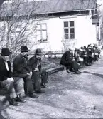 Foto av ett gäng arbetare som sitter på ett staket. Bildtext i album: 