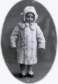 Foto av ett barn i vinterkläder. Bildtext i album: 