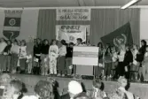 Barn på Fässbergsgymnasiets aulas scen vid en sammankomst för Unicef. Mölndal i slutet av 1980-talet eller i början av 1990-talet.