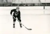 En ung ishockeyspelare på ishockeyskolan. Fotografiet är taget vid Mölndals konstisbana vid Ågatan i Trädgården, Mölndal, ca 1970-1976.
