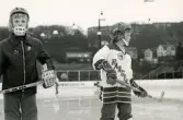 Två unga ishockeyspelare på ishockeyskolan. Fotografiet är taget vid Mölndals konstisbana vid Ågatan i Trädgården, Mölndal, ca 1970-1976.