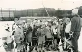 Unga ishockeyspelare på ishockeyskolan. Ledare är Per Adolfsson. Fotografiet är taget vid Mölndals konstisbana vid Ågatan i Trädgården, Mölndal, ca 1970-1976.
