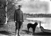 Man poserar i properklädsel med hund vid sin sida.