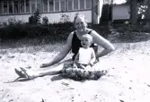Foto av kvinna och barn som sitter på stranden.