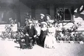 Foto av Per Johan Haegerstrand sittandes på trädgårdsstol med familj bredvid sig och hund vid sina fötter, Gröndal sommaren 1902.