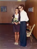 Karin Pettersson (gift Hansson), klädd i brudklänning och med en blombukett i handen, står jämte sin blivande man Esbjörn i Mölndals stadshus inför vigseln 1973-09-29.
