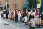 Nationaldagsfirande i Stadshusparken i Mölndal den 6 juni 1999. Här ses en samling människor iförda bygdedräkter tåga in på Häradsgatan.