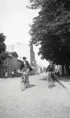 Sparbanksfastigheten på Kungsgatan, kv. Sunaman, innan nybyggnation, följd av bla Frimurarnas fastighet i kvarteret Vinaman, ca 1927.
Några pojkar cyklar i full fart mot fotografen.