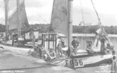 Båten Flygia FG 36 vid kaj, bakom båten Göta.  Framför styrhytten Sven-Olof Johansson, sittande t.v. Algot Olsson, längst t.v. delvis skymd Johan Olsson (dessa två ägde båten), sittande med ena benet på kajen Sten Karlsson. I fiskebåten Göta finns Gustav Johansson, Oskar Bengtsson, troligen Axel Bengtsson och en okänd.  Från Hallands Nyheter, odaterad.