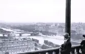 Foto av en man som från en hög byggnad tittar ut över floden Seine och staden Paris, 1921.