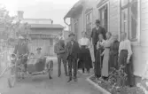 Fotot gåva av Ingeborg Hellberg Torggatan 6 D 311 31 Falkenberg, den 7 nov 1989.  De boende i kv. Svärdet 5 uppställda utanför bostadshuset 1921.  Fr.v. Erik Hjalman (på motorcykeln), Ingeborg Kronvall, Britta Kronvall, uppgift saknas, Per-Harry Kjellberg, skräddare Emil Svensson (hyresgäst) och hans hustru Alma (sömerska), Karl Kronvall och hans hustru Hilma, Amanda Kronvall och hennes mor Lena-Beata, Potensia Persson (trotjänarinna hos Kronvalls)