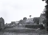 Foto av en by med hus av halmtak vid Normandie, 1921.