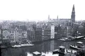 Vy över en kanalstad, troligen Amsterdam i Nederländerna, med flera byggnader längs vattnet och båtar i kanalen, 1924.